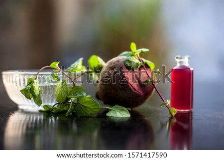 Fresh raw sliced beetroot along with some mint leaves and its extracted essence oil in a tiny glass bottle.Horizontal shot with blurred background.
