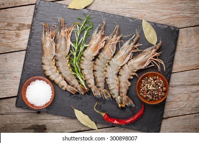 Fresh Raw Tiger Prawns And Spices On  Black Stone Plate Over Wooden Table