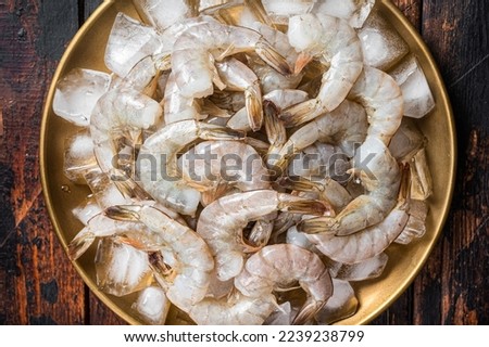 Fresh Raw tiger white shrimp prawn peeled with tail on ice. Wooden background. Top view.