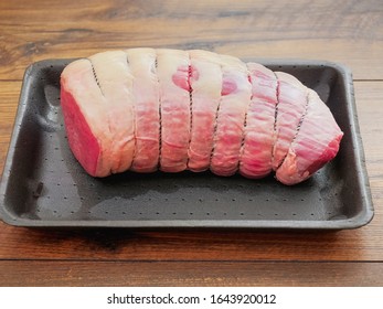 Fresh raw uncooked eye of round roast on a black plastic tray and wooden table, Prime cut of beef. Tied with string to keep shape. - Powered by Shutterstock