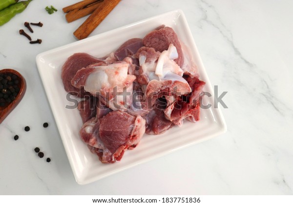Fresh raw, uncooked goat meat or mutton or\
lamb pieces. Preparation for Indian mutton curry. Spice at the\
background such as cinnamon sticks, red chili powder, black pepper\
& coriander. Copy\
space.\
\
