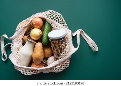 Fresh raw vegetables, a bottle of milk and beans in a mason jar in a reusable mesh shopping bag on a green table. Top view.  - Powered by Shutterstock