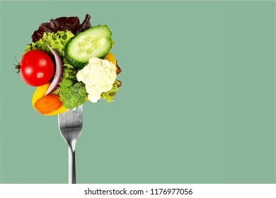 Fresh Raw Vegetables On Fork On Blue Background