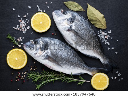 Fresh ready to cook raw gilt-head bream (dorade) fish with ingredients and seasonings.