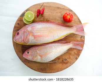  Fresh and ready to cook raw pink Perch fish with ingredients like lemon,chilli and tomatoes on a wooden pad,white background, selective focus.