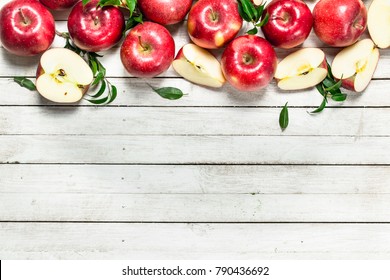 Fresh red apples with leaves. On a white wooden background.