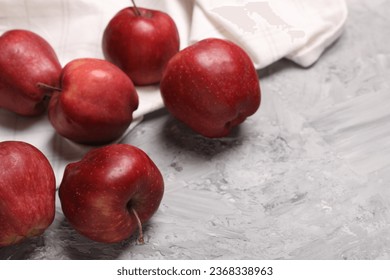 Fresh red apples on grey textured table, closeup. Space for text