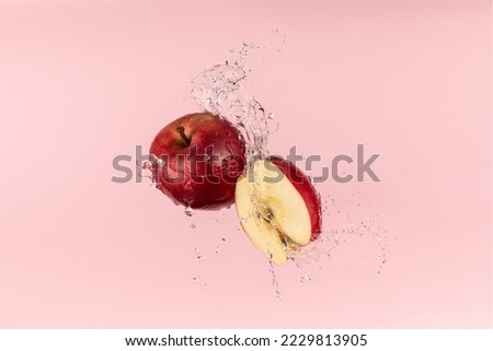 Fresh red apples on pink background with water splash
