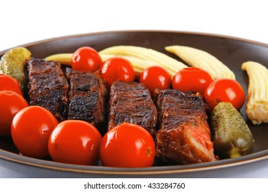 fresh red beef meat served with baby corns and cherry tomatoes on dark plate isolated on white background