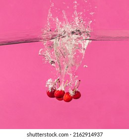 Fresh red cherry fruits water splash. Minimal food concept. Summer bold pink background.