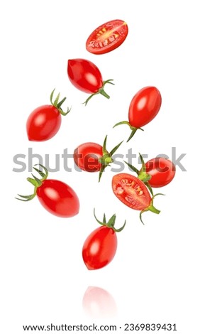 Fresh red cherry tomatoes with half sliced falling isolated on white background