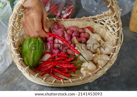 Fresh red chilies in woman's hands on basket background
