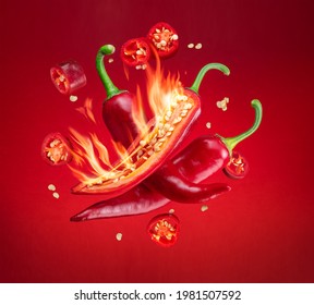 Fresh red chilli pepper in fire as a symbol of burning feeling of spicy food and spices. Red background.