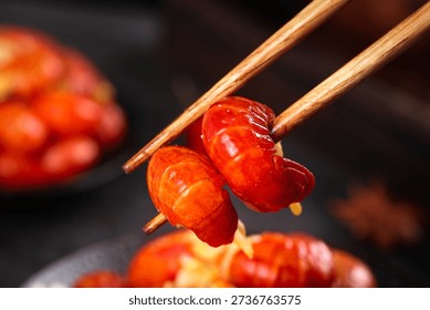 Fresh red crayfish tail held with chopsticks, showcasing spicy Asian cuisine. Delicious seafood ready for instant cooking and serving.