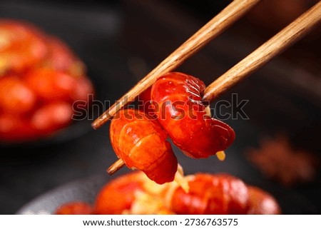 Fresh red crayfish tail held with chopsticks, showcasing spicy Asian cuisine. Delicious seafood ready for instant cooking and serving.
