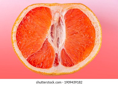 Fresh red cut grapefruit on pink background. Female health concept. Fruit as symbol of vagina. Close up