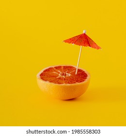 fresh red grapefruit with red parasol on yellow illuminating background. modern summer abstract art. minimalism. - Shutterstock ID 1985558303