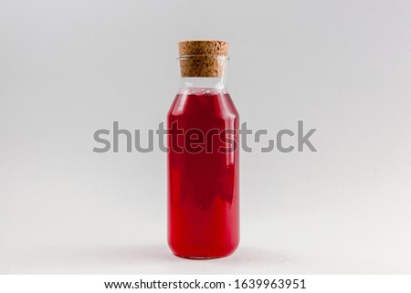 Fresh red juice in bottle with cork isolated on white background. Cherry, pomegranate, strawberry, rasberry, grape or another berry juice.