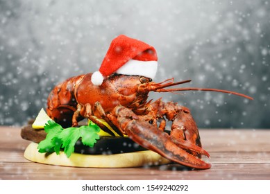 Fresh Red Lobster With Christmas Hat Shellfish Cooked In The Seafood Restaurant / Steamed Lobster Dinner Food On Wooden Christmas Table Setting With Snow Celebrate In Holiday Winter Festive