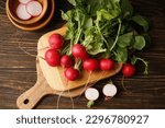 Fresh red radish and kitchen board on wooden background. Flat lay.