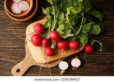 Fresh red radish and kitchen board on wooden background. Flat lay.