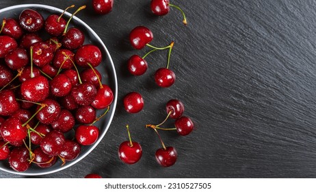 Fresh red ripe sweet cherry with water drops on plate on black slate, stone background. Berry, food background. Top view, banner, header with copy space. - Powered by Shutterstock