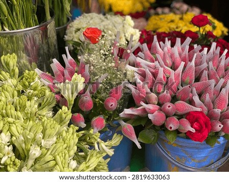 Fresh red roses with protective netting and white tuberoses at market