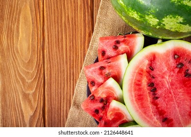 Fresh red watermelon pieces on a black plate on a wooden table. Sweet and juicy watermelon.