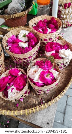 Fresh red and white roses and petals in woven bamboo basket being sold in flower market, for use in wedding ceremony. Natural ingredients of essential oil, cosmetic products, fragrances or herbal tea.