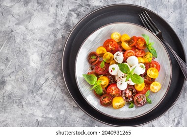 Salade de tomate de cerise rouge et jaune fraîche avec fromage bébé mozzarella et basilic, en gros plan