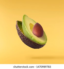 Fresh ripe avocado falling in the air isolated on yellow background