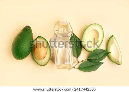 Fresh ripe avocados and glass bottle with essential oil on beige background