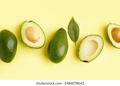 Fresh ripe avocados and leaf on yellow background