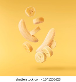 Fresh ripe baby bananas falling in the air isolated on yellow background. Food levitation concept. High resolution image