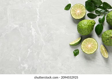 Fresh ripe bergamot fruits with green leaves on light grey marble table, flat lay. Space for text