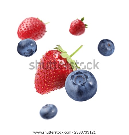 Fresh ripe blueberries and strawberries falling on white background