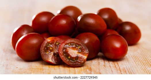 Fresh ripe cherry kumato tomatoes grown by selected farmers on wooden surface - Shutterstock ID 2227729345