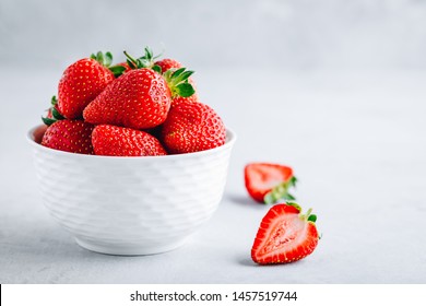 Fresh ripe delicious strawberries in a white bowl on a gray stone background