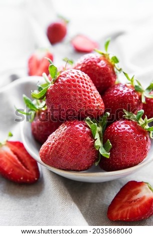 Fresh ripe delicious strawberries in a white bowl on a gray textile background