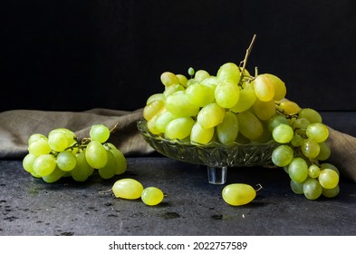 Fresh ripe green grapes in a glass fruit bowl on black background