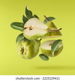 Fresh ripe green pear with leaves falling in the air, isolated on green background. Food levitation or zero gravity concept. High resolution image - Shutterstock ID 2223129411