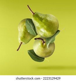 Fresh ripe green pear with leaves falling in the air, isolated on green background. Food levitation or zero gravity concept. High resolution image