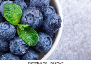 Fresh Ripe And Juicy Blueberries With Drops Of Water. White Bowl. Mint Leaf. Macro Photo - Image