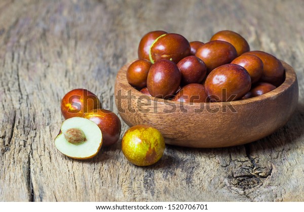 Fresh ripe jujube fruits in bowl on wooden rustic\
background. Healthy fruit cleans blood, contains vitamin c (\
Ziziphus zizyphus )