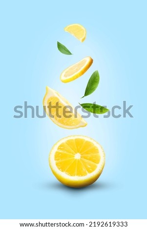 Fresh ripe lemons and green leaves falling on light blue background