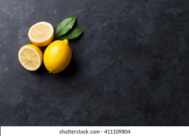 Fresh ripe lemons on dark stone background. Top view with copy space