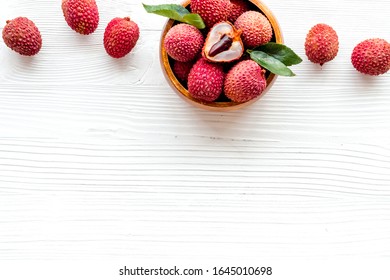 Fresh ripe lychee in bowl on white wooden desk top-down frame copy space