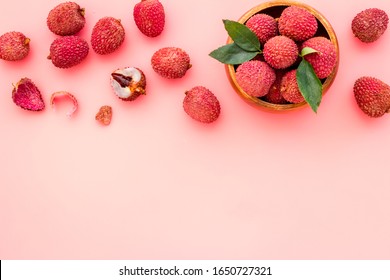 Fresh ripe lychee in bowl on pink desk top-down frame copy space