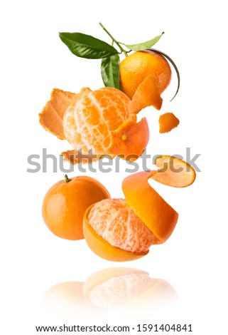Fresh ripe mandarine with leaves falling in the air. Cut and whole mandarine isolated on white background. Food levitation concept. High resolution image