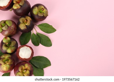 Fresh ripe mangosteen fruits with green leaves on pink background, flat lay. Space for text